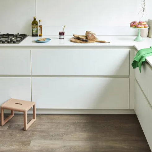 Close-up of Amtico Spacia Heritage Oak luxury vinyl flooring, complementing a minimalist white kitchen. Durable, stylish, and water-resistant – ideal for busy homes. LuxeFloors Co.