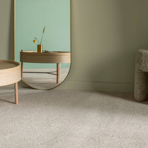Balta Classic Charm carpet in Heathers (beige), shown in a stylish room with a minimalist table and mirror, captured from a slightly shifted right-angle perspective, maintaining a warm and elegant ambiance.