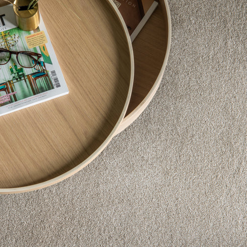 Balta Classic Charm carpet in Heathers (beige), captured from a top-down view, featuring a table with a magazine, glasses, and a pen pot, creating a stylish and cozy setting.