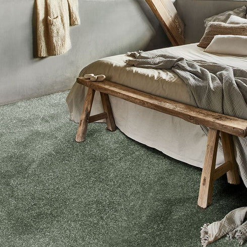 Luxurious GAIA® Dorado carpet in an elegant olive green shade, complementing a serene bedroom setting with soft textures and a warm, inviting ambiance.