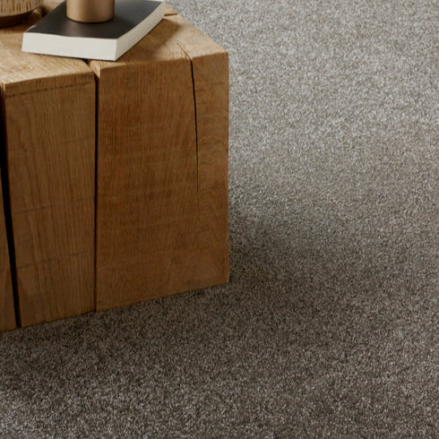 Lano Felicity carpet in Leather (grey), elegantly laid beneath a wooden table, highlighting its soft texture and sophisticated design in a modern interior setting.