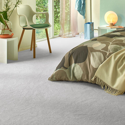 Sedna® Kai carpet in a cool light grey, complementing a serene bedroom with neutral decor.