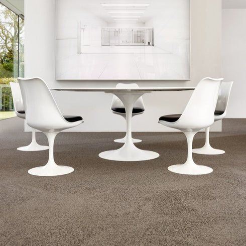 Lano Romance carpet in Angora (beige), elegantly placed beneath a sleek white table and chairs, complementing a modern aesthetic in a sophisticated interior setting, possibly an office or design studio.