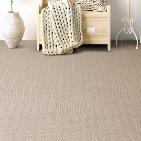 Riviera Home Sorrento Carpet in a cozy, modern interior featuring a soft beige wool flatweave with a subtle chevron pattern, complementing natural wood furniture and neutral decor.