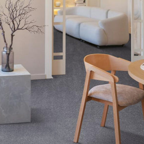Balta Crescent carpet in grey, enhancing a simple interior with a warm, modern aesthetic, complemented by a wooden chair for a natural and elegant touch.