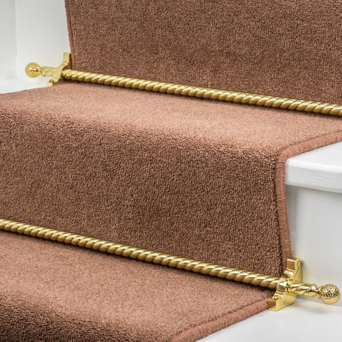 Stairrods UK Eastern Promise Dune in brass, beautifully fitted on a brown beige carpet runner, enhancing the elegance of white wooden stairs with a classic gold finish.